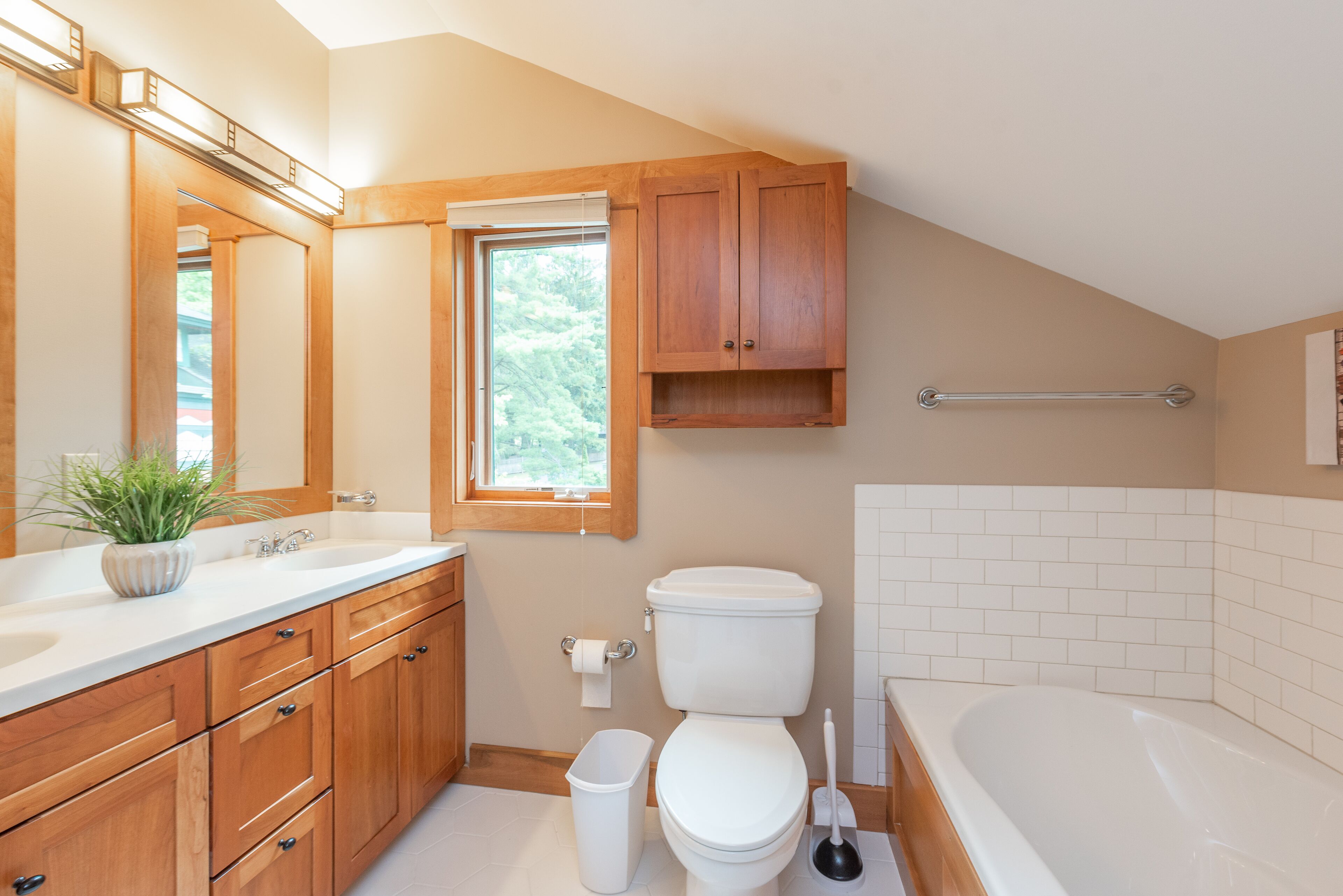 Een badkamer met houten kastjes, een witte wastafel, een toilet en een bad.