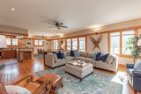 A spacious living area with a large sectional sofa, a wooden coffee table, and a dining area with a table and chairs.