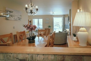 A dining area with a wooden table, chairs, a chandelier, and a vase with flowers.