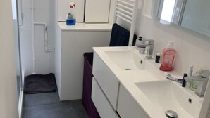 A modern bathroom with a white sink, mirror, and towel rack.