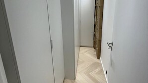 A narrow hallway with a herringbone-patterned floor, white walls, and a door on the right.