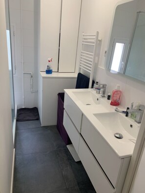 A modern bathroom with a white sink, mirror, and towel rack.