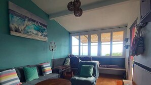 Una sala de estar con un sofá, sillones, una mesa de centro y un cuadro en la pared.