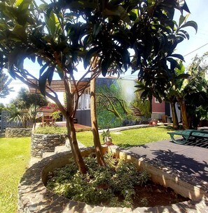 A garden with a stone planter, a wooden bench, and a mural on the wall.