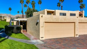 A modern two-story house with a beige exterior, a garage, and a well-maintained lawn. - Corsican Villas 2BD Condo- Near Living Desert (Palm Desert)
