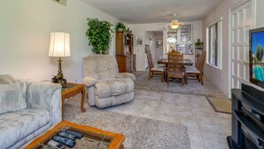 A living room with a sofa, armchair, coffee table, and a television. - Corsican Villas 2BD Condo- Near Living Desert (Palm Desert)