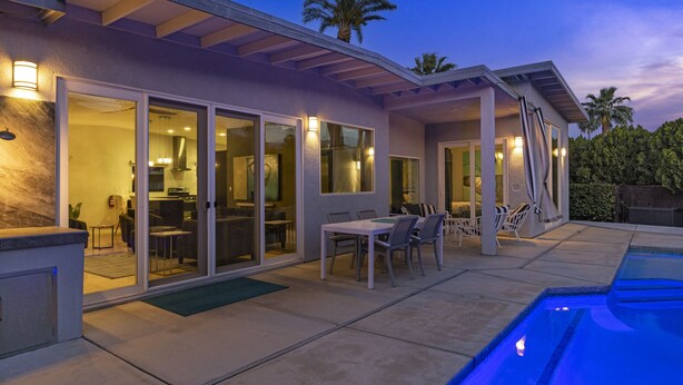Ein modernes Haus mit Pool, Schiebegläsern und Sitzgelegenheiten im Freien.