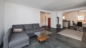 A modern living room with a grey sofa, a glass coffee table, and a rug.