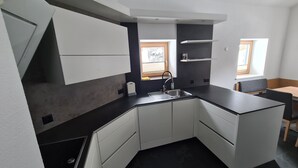 A compact kitchen with white cabinets, a black countertop, and a window providing natural light.