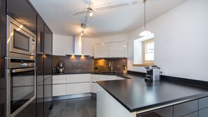 A modern kitchen with a large island, built-in appliances, and a window providing natural light.