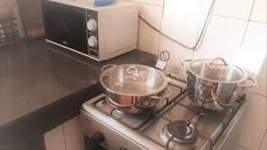 Une cuisine équipée d’une cuisinière, avec deux casseroles sur les brûleurs, un grille-pain et une bouilloire posée sur le plan de travail.