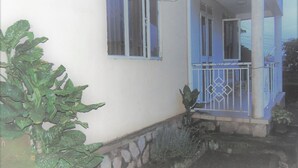 Une maison avec des fondations en pierre, une porte bleue et un petit balcon doté d’une balustrade blanche.