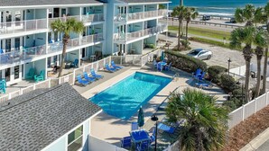 A multi-story hotel with a swimming pool, outdoor seating, and a view of the ocean. - 🌊Ground Floor | Beach Front | Upscale + Disc. Beach Service-Beach Blessing🌊 (Miramar Beach)