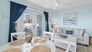 A room with a dining table, chairs, a sofa, a ceiling fan, and a view of the outside. - 🌊Ground Floor | Beach Front | Upscale + Disc. Beach Service-Beach Blessing🌊 (Miramar Beach)