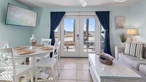 A room with a dining table, chairs, a sofa, a ceiling fan, and a view through a glass door. - 🌊Ground Floor | Beach Front | Upscale + Disc. Beach Service-Beach Blessing🌊 (Miramar Beach)