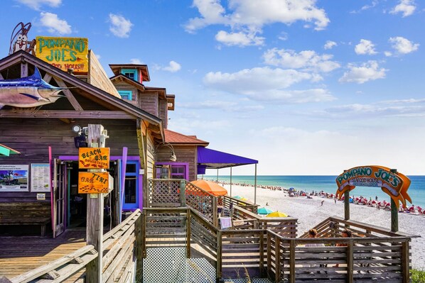A wooden building with a beach bar and a seafood house sign.