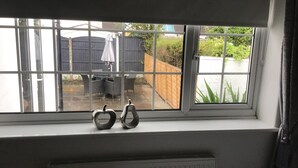 Una ventana con vista a un patio trasero, una valla de madera y una mesa con sillas.