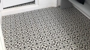 Una puerta blanca con manija de latón, un ventanal encima y un suelo con diseño.