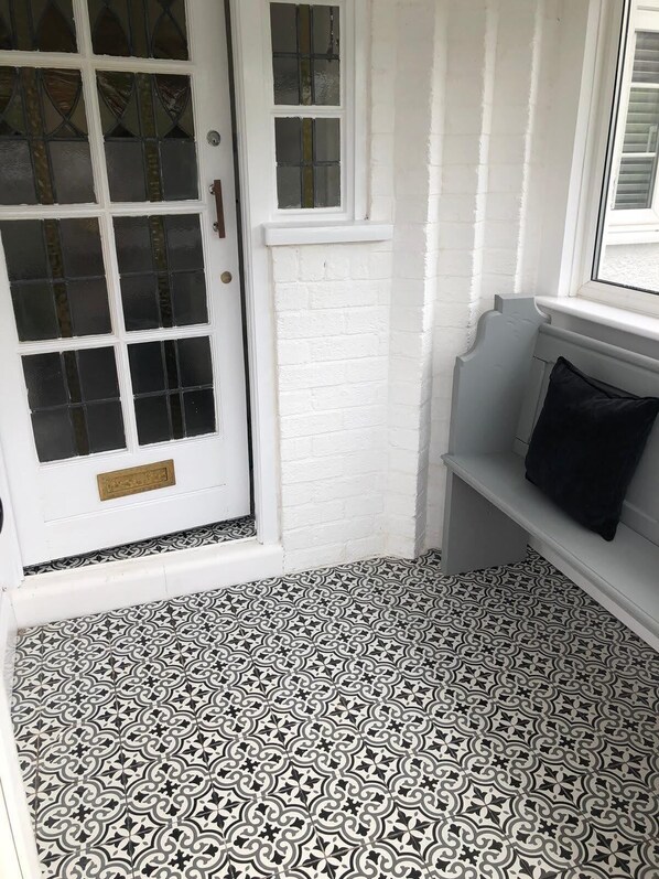 A white door with a brass handle, a small window above it, and a patterned floor.