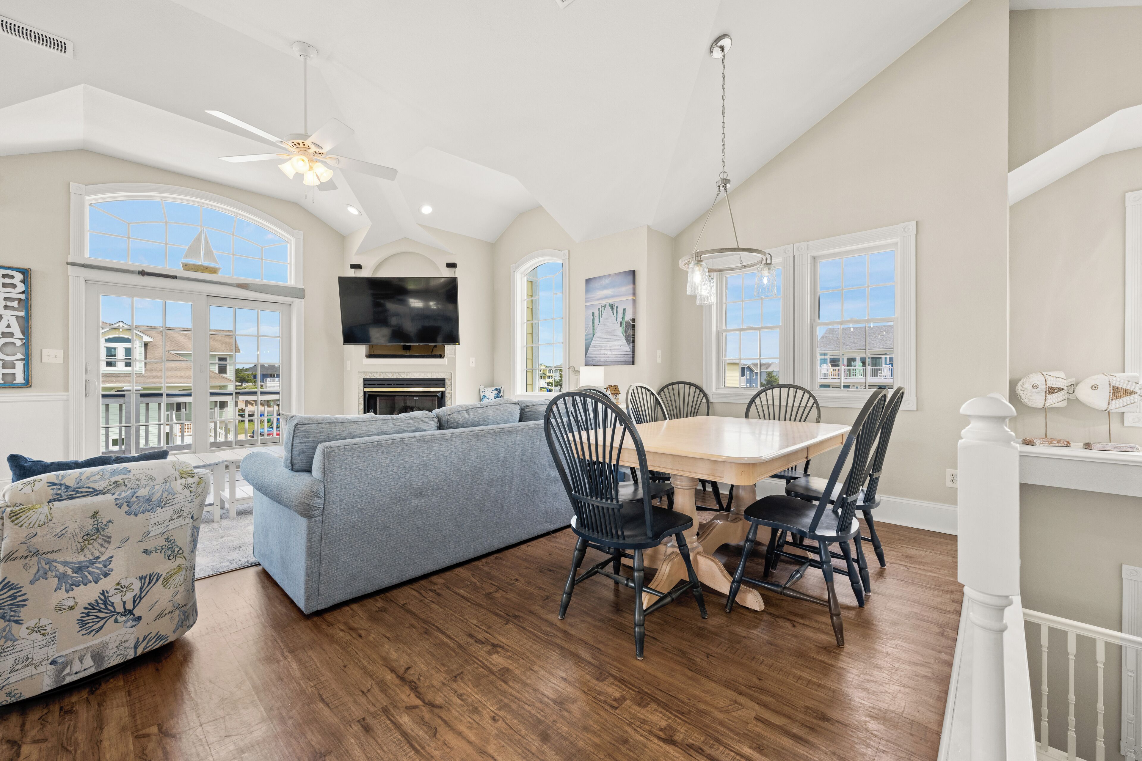 A spacious living room with a large gray sofa, a dining table with chairs, and a ceiling fan.