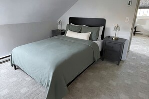 A bedroom with a bed, two bedside tables, and a nightstand.