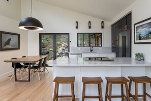 Una cocina moderna con una isla grande, taburetes de madera y una mesa de comedor con sillas.