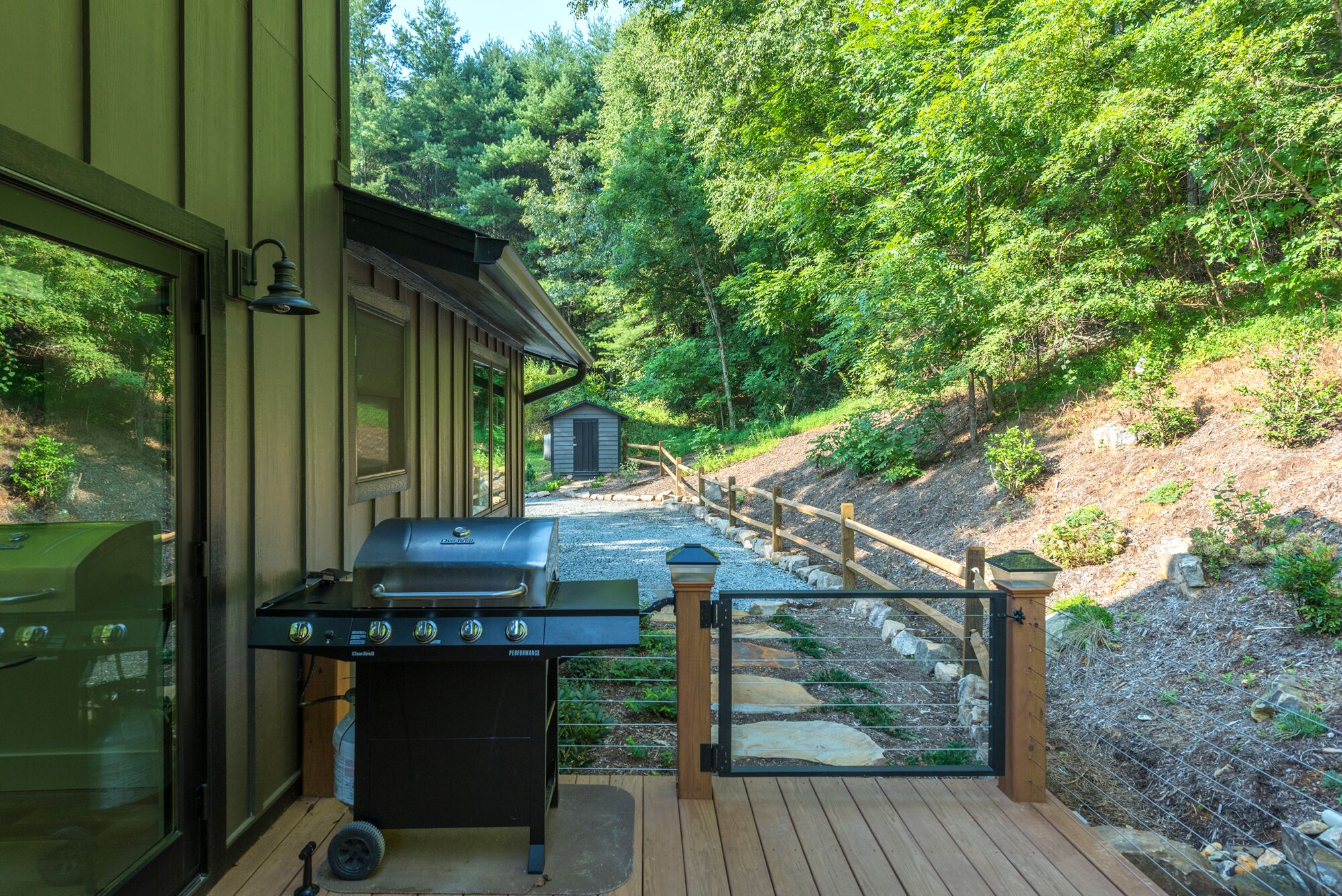An outdoor grill area with a wooden deck and a view of a forested hillside.