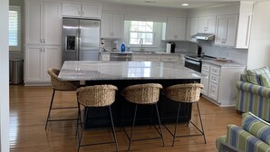 A modern kitchen with white cabinetry, a stainless steel refrigerator, and a central island with bar stools.