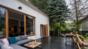 A modern outdoor deck with a gray sofa, wooden table, and a grill area. - Secret Loft by Villa Jurka (Paszkówka)