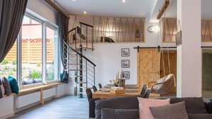 A modern living room with a sofa, a dining table, and a staircase leading to an upper level. - Secret Loft by Villa Jurka (Paszkówka)
