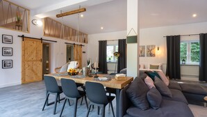 A modern living room with a dining area, a large sofa, and a swing chair. - Secret Loft by Villa Jurka (Paszkówka)