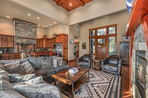 A spacious living room with a stone fireplace, leather chairs, a sofa, and a coffee table.