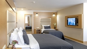 A hotel room with two beds, a TV, a mirror, and a small table with a vase. - Merlin Hotel Istanbul (Istanbul)