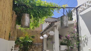 A cozy outdoor seating area with a stone wall, potted plants, and hanging lanterns. - Bright and airy townhouse (Soller)