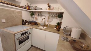 A compact kitchen with a built-in oven, a sink, and a countertop with various kitchen items. - Bright and airy townhouse (Soller)