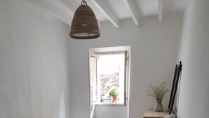 A bedroom with a bed, a window, a bedside table with a plant, and a small stool. - Bright and airy townhouse (Soller)