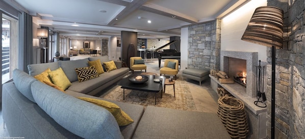 A modern living room with a grey sofa, yellow cushions, a black coffee table, and a stone fireplace. - Wifi, 20m from ski slopes, fitness, swimming pool, sauna, hammam, balcony, tv, ski locker, 44m² (Le Grand-Bornand)
