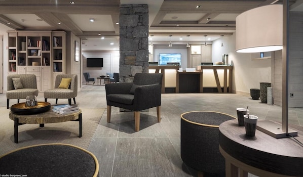 Een moderne woonkamer met een stenen zuil, een salontafel en zithoeken.