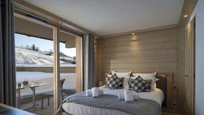 Une chambre à coucher avec un grand lit, une table de chevet et une vue sur un paysage enneigé, visible à travers une porte coulissante.