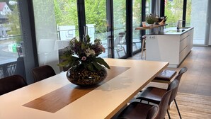 A modern dining area with a long table, chairs, and a kitchen island.