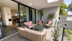 A modern living room with a sofa, chairs, a coffee table, and a potted plant.