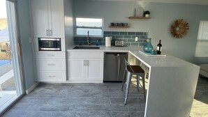 Een moderne keuken met witte kasten, een inbouwoven, een spoelbak en een bar met krukken.
