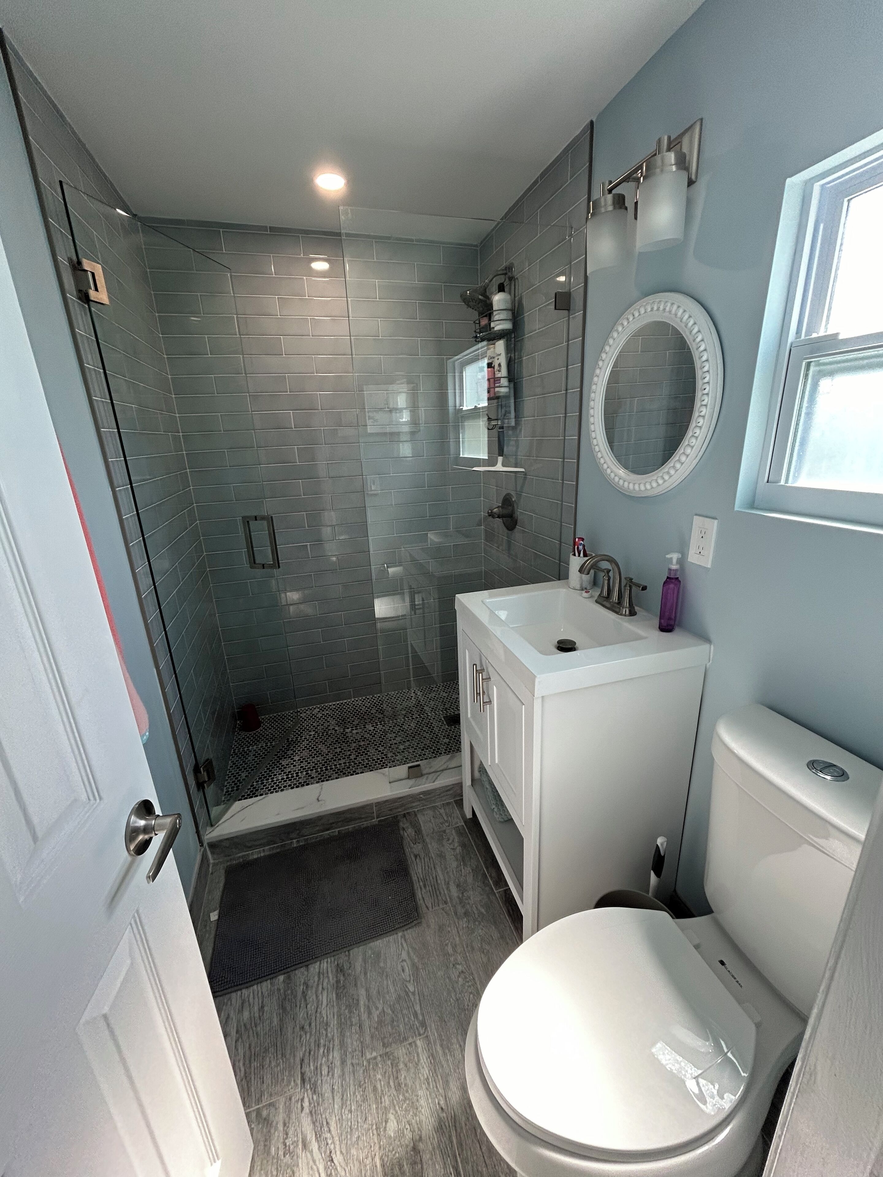 A modern bathroom with a glass shower enclosure, a white sink, and a toilet.