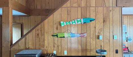 A kitchen with wooden paneling, a microwave, toaster, and a decorative fish on the wall.