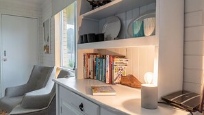 A modern living room with a built-in bookshelf, a comfortable armchair, and a table with a lamp.