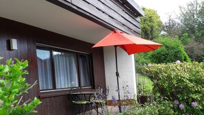 Una casa moderna con patio, tavolo da pranzo e ombrellone.