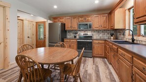 Una cocina con armarios de madera, un refrigerador de acero inoxidable, un microondas y un horno.