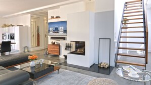 Un salon moderne avec une table basse en verre, un canapé, une cheminée et un escalier en bois.