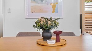 Une table en bois sur laquelle se trouvent un vase de fleurs et un bol rouge, le tout posé sur un plateau rond en bois.