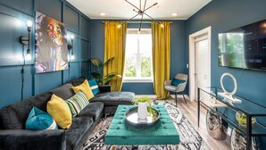 A modern living room with a sectional sofa, a glass coffee table, and a large painting on the wall. - Cozy Modern Home in Downtown Atlanta (Atlanta)